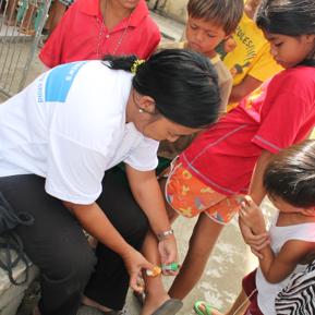 An SOS nurse providing first aid to a girl, other children standing around looking at them Tacloban An SOS nurse providing first aid to a girl, other children standing around looking at them Tacloban