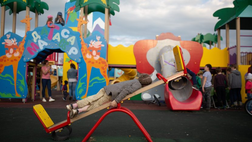 bambino sdraiato sull'altalena in un parco giochi