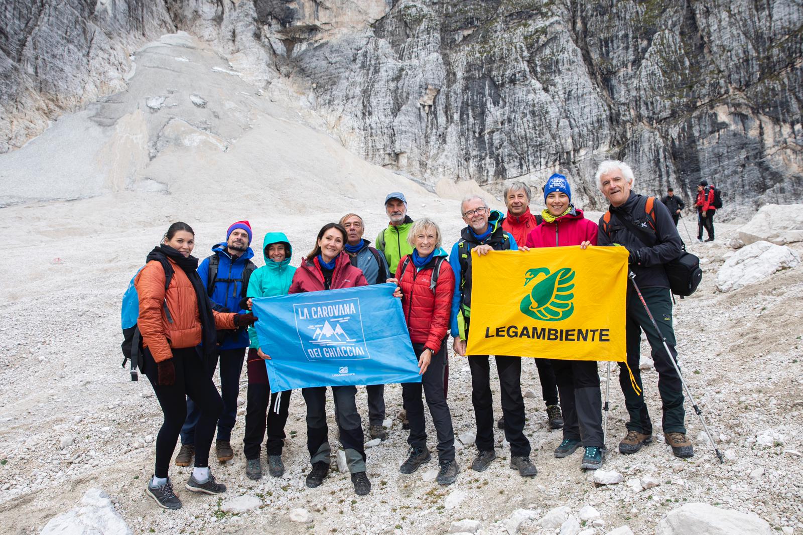Gruppo di persone in montagna, tengono in mano la bandiera di Legambiente e quella della Carovana dei ghiacciai