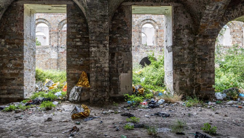 Dettaglio del silos di Trieste, due archi in muratura tra cui crescono erbacce. Abbandonate, alcune coperte termiche
