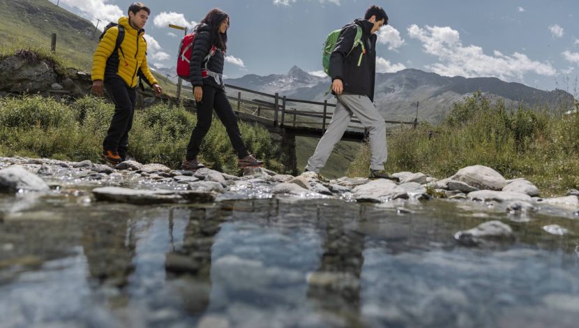 Tre persone vestite da trekking prese dal basso, che camminano nella natura
