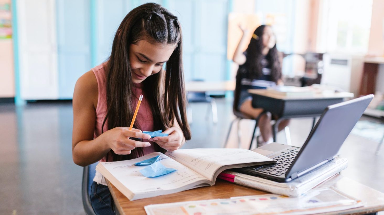 ragazzina al banco di scuola con libri e computer