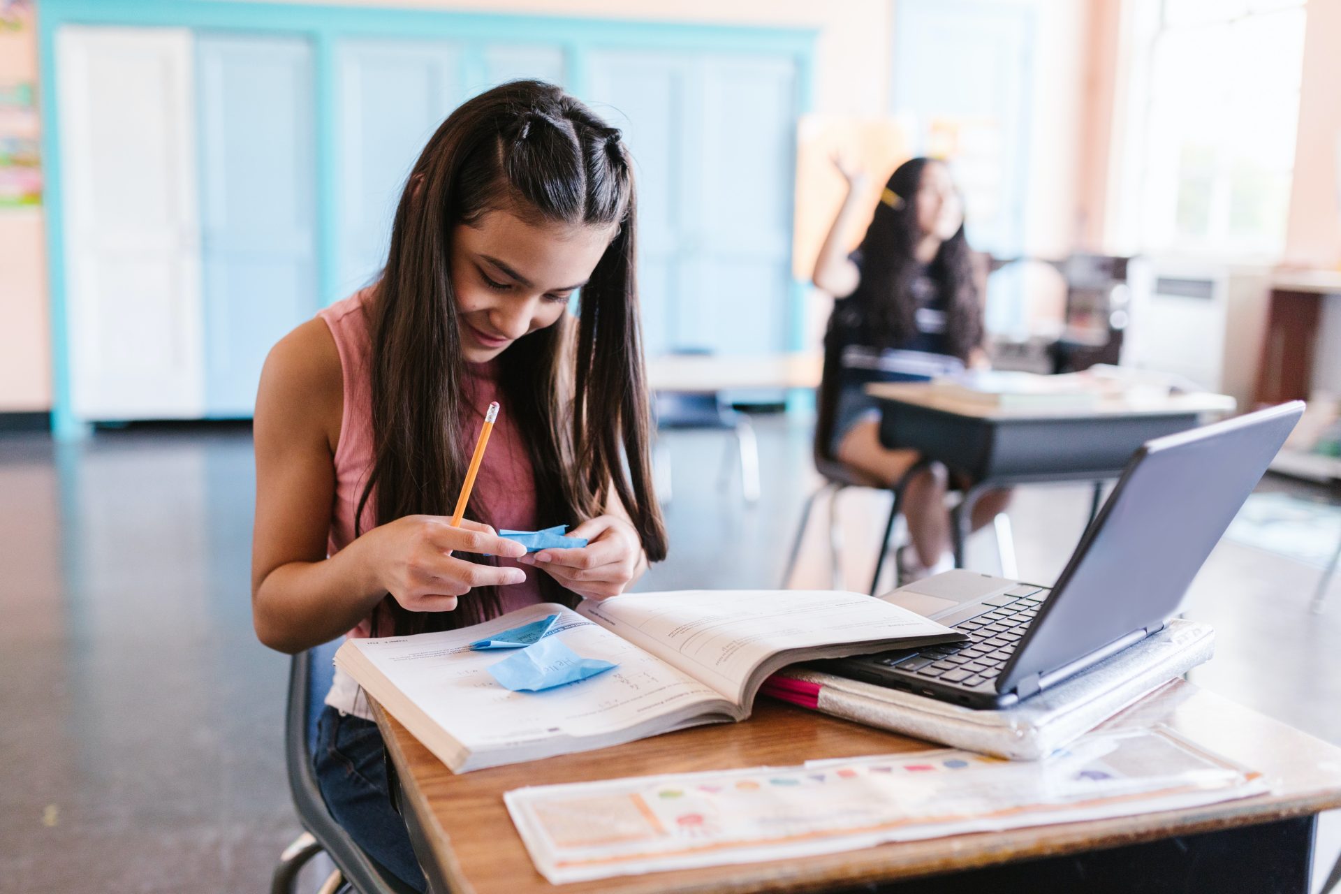 ragazzina al banco di scuola con libri e computer