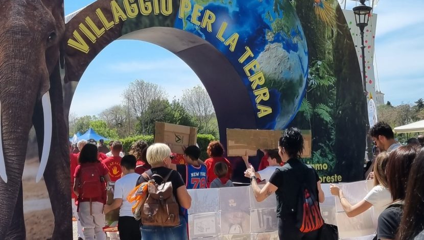 Un arco con scritto Villaggio della Terra e dei bambini che entrano attraverso l'arco