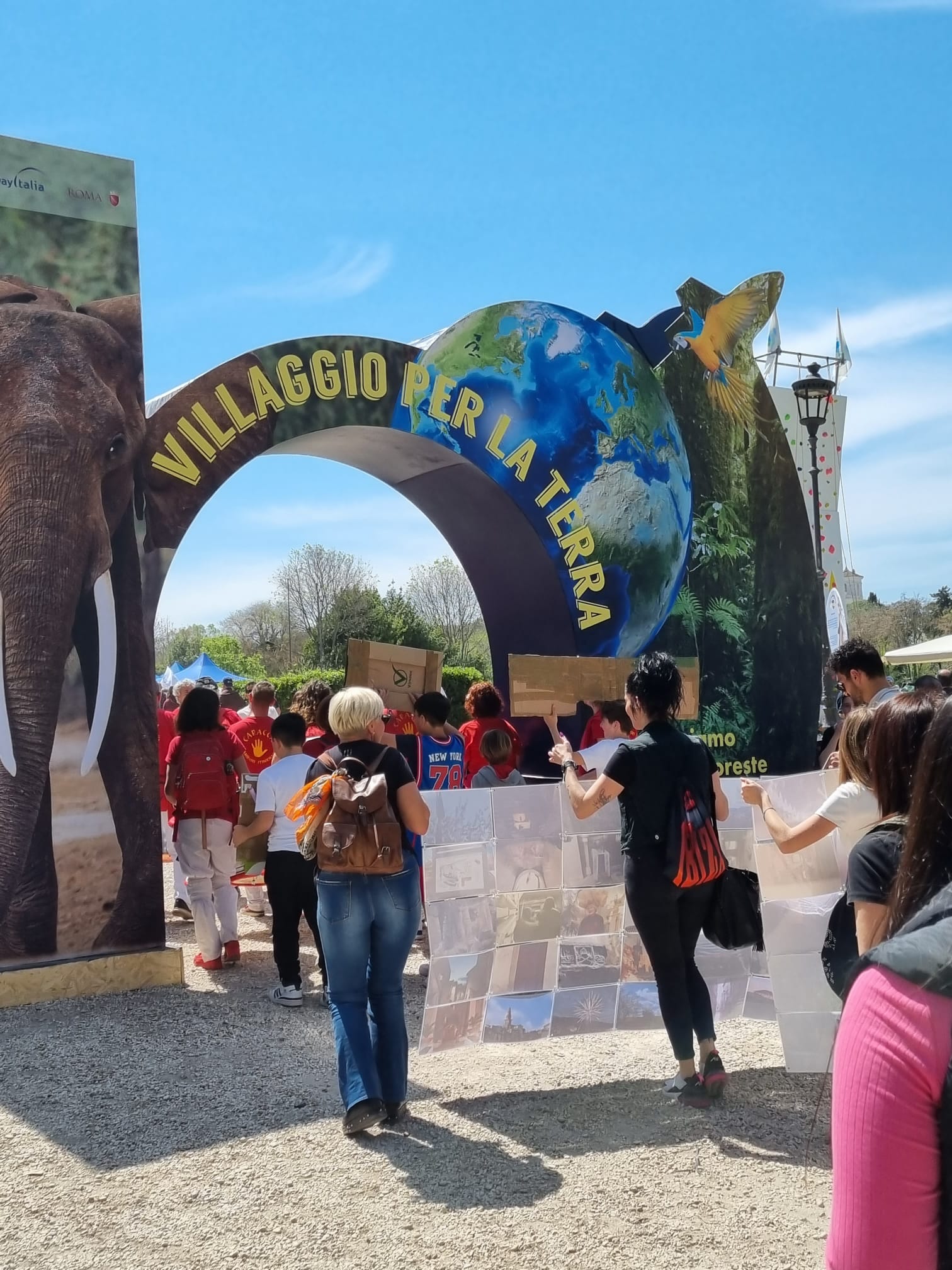 Un arco con scritto Villaggio della Terra e dei bambini che entrano attraverso l'arco