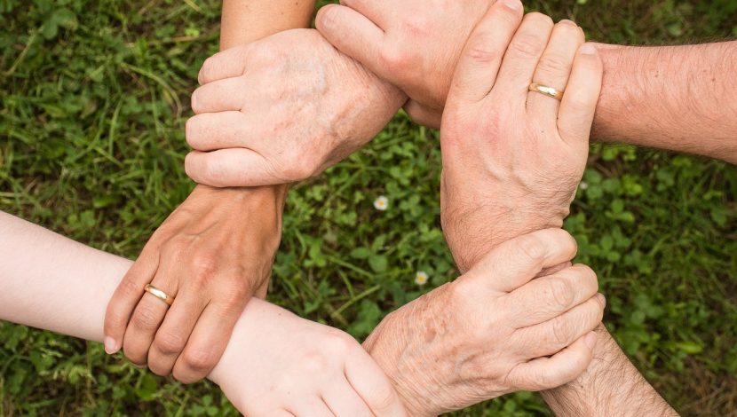 6 mani che si stringono in cerchio, prendendosi per i polsi