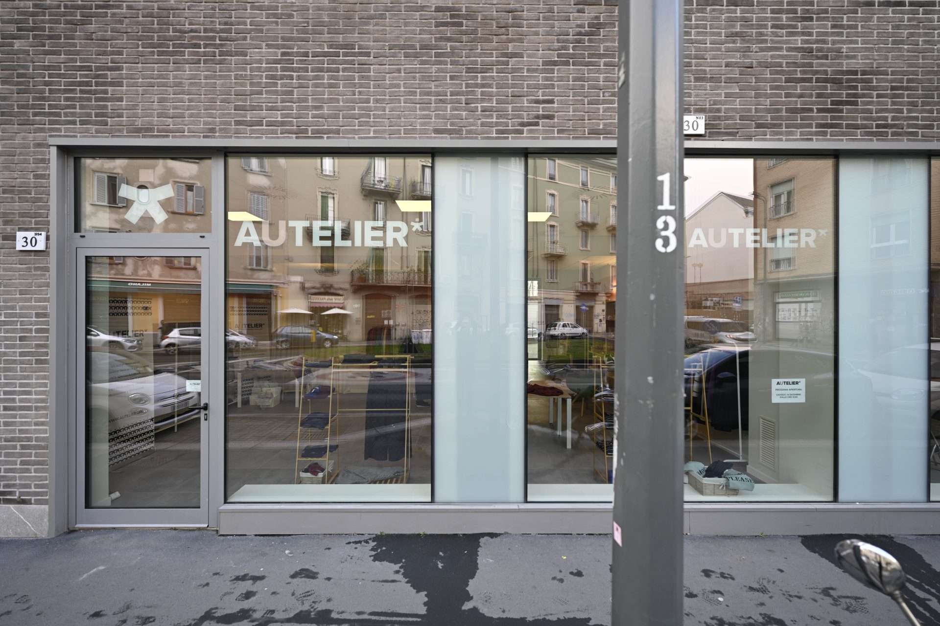 L'esterno del negozio visto dalla strasa, due vetrine con scritto "Autelier"