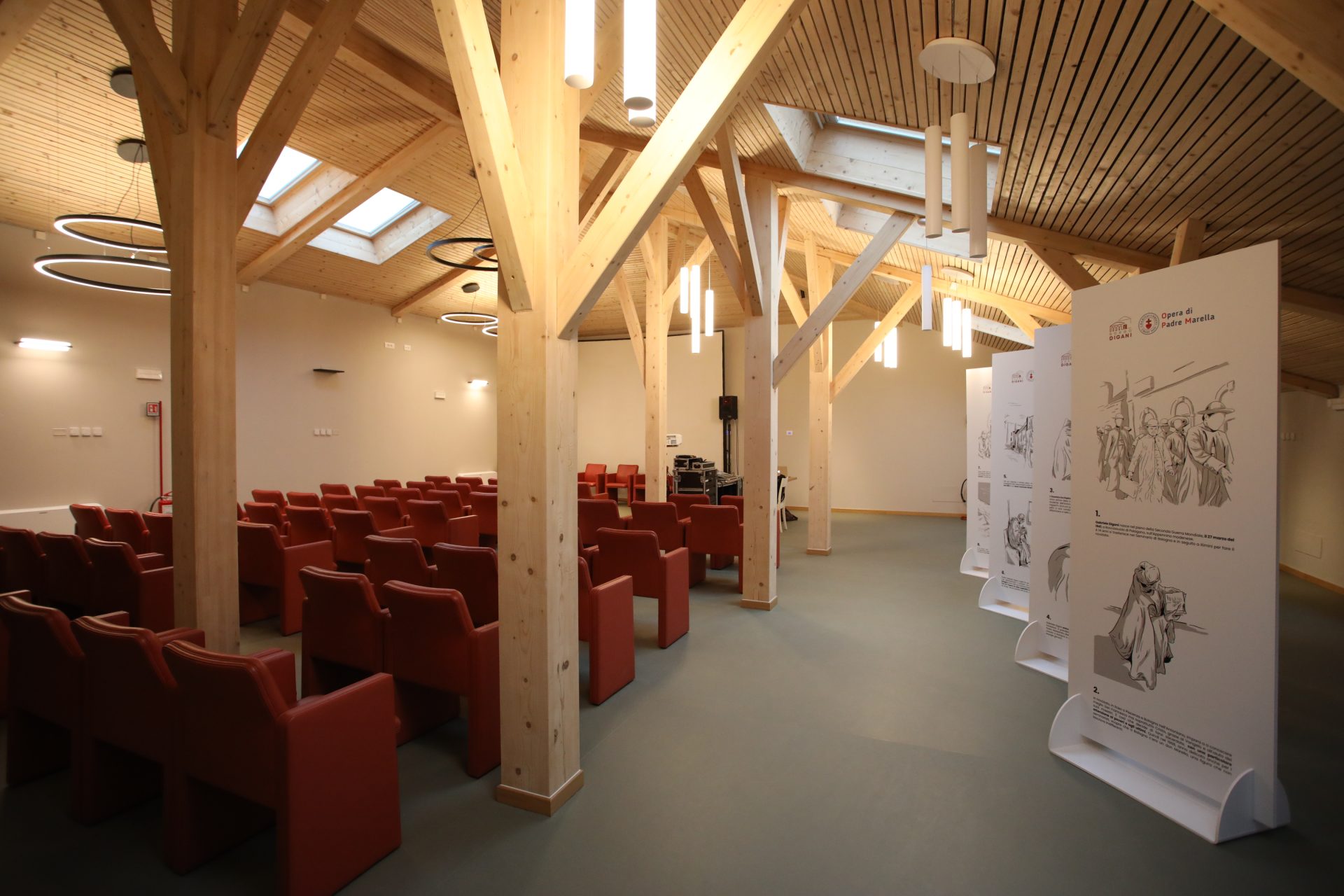 L'interno dell'auditorium, realizzato in legno chiaro e con sedie rosse, sulla destra una serie di pannelli bianchi con scritte