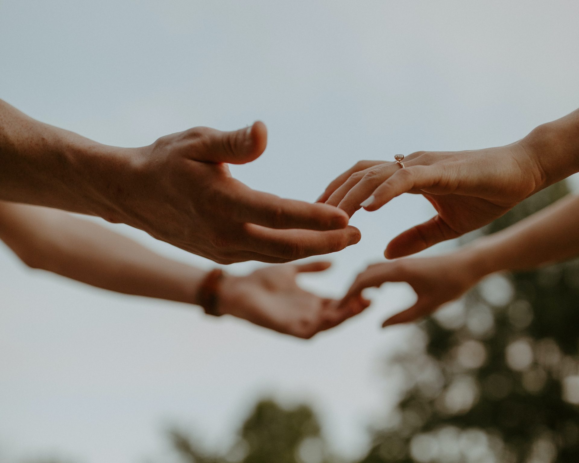 Dettaglio delle mani di due persone, una di fronte all'altra all'aperto, mentre si stanno sfiorando