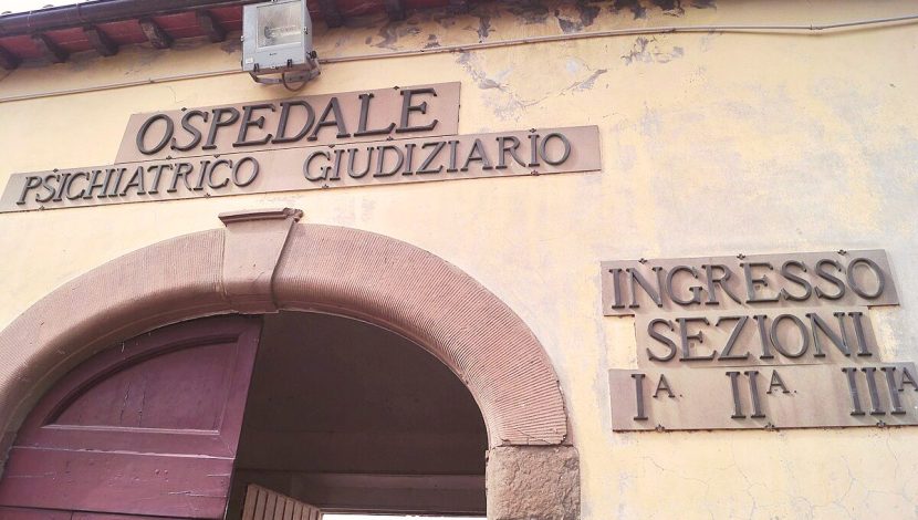 Sezione di una porta ad arco, in stile antico, con scritto sopra "Ospedale psichiatrico giudiziario"