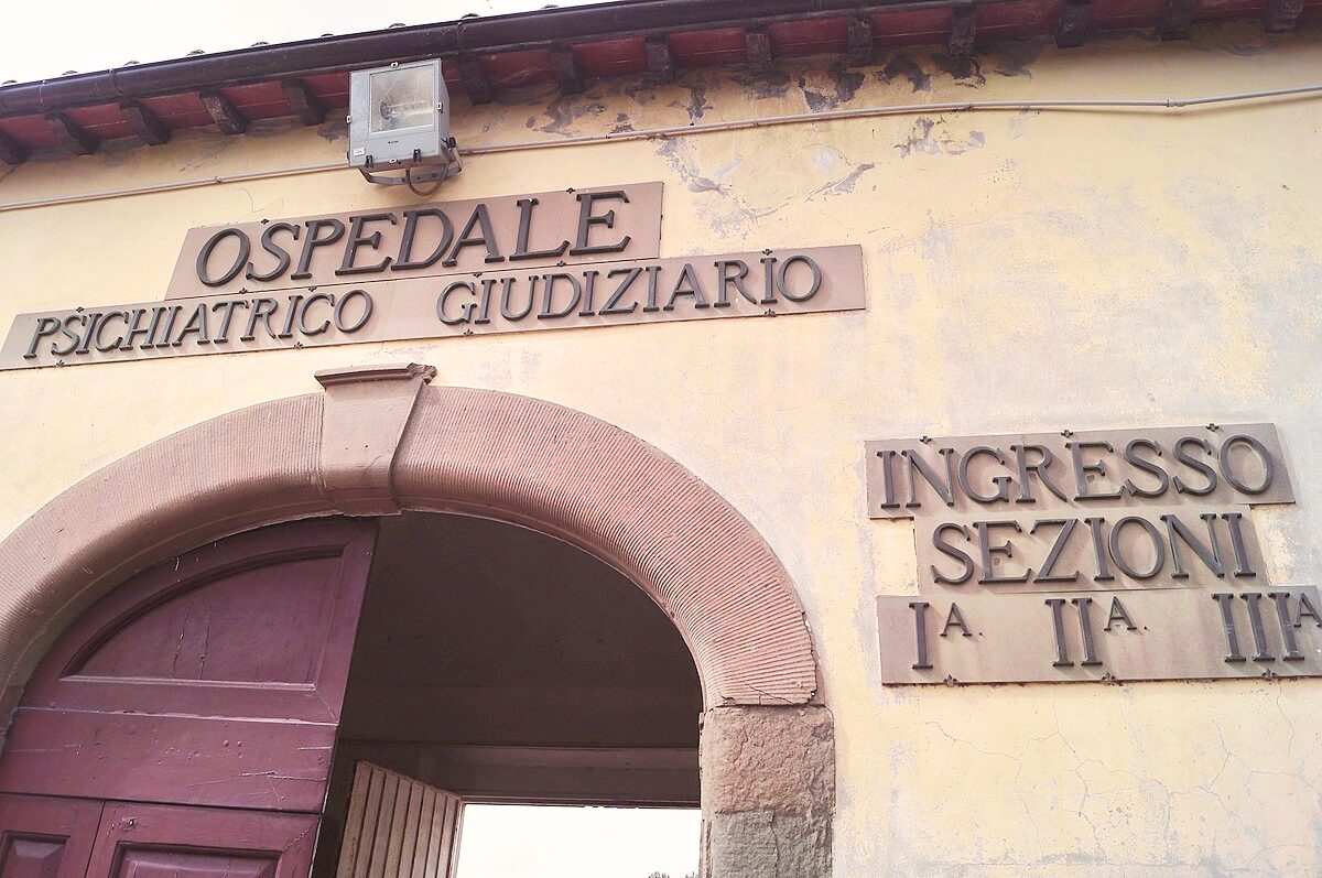 Sezione di una porta ad arco, in stile antico, con scritto sopra "Ospedale psichiatrico giudiziario"