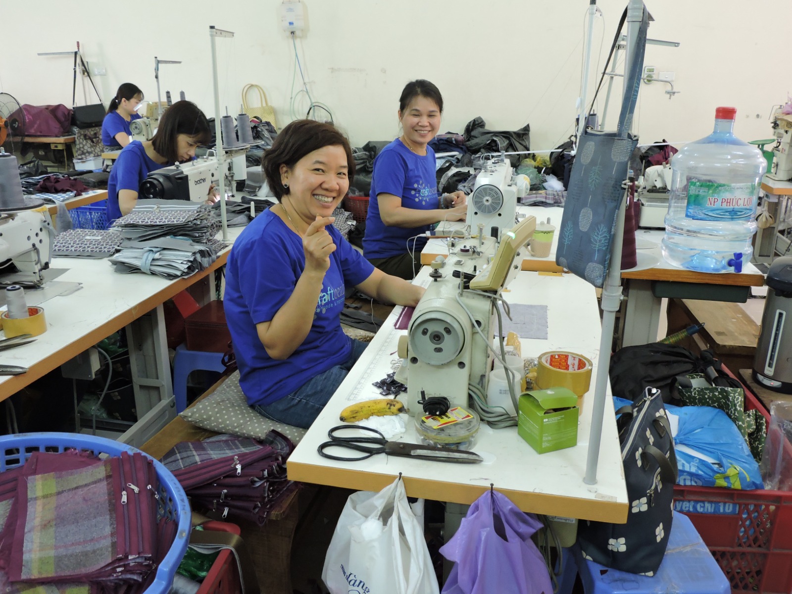 delle persone orientali sedute a un tavolo di una fabbrica di abbigliamento