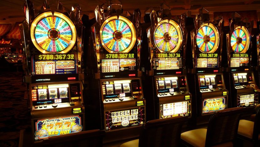 Quattro slot machine una vicino all'altra, con ruote colorate e scritte su sfondo buio