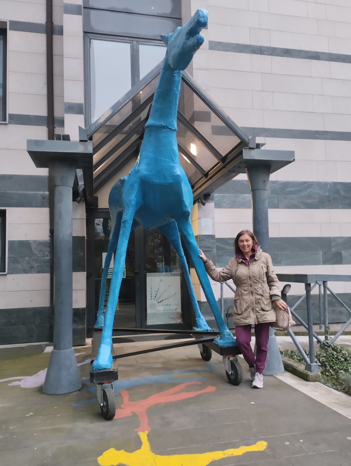 La grande statua di un cavallo blu sotto una tettoia, appoggiata a essa, una persona 