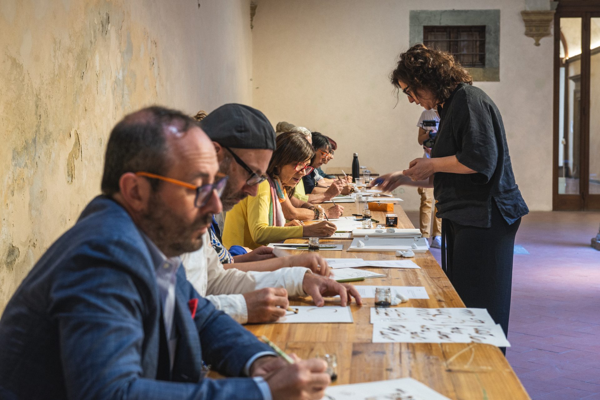 persone sedute a un tavolo, scrivono delle lettere