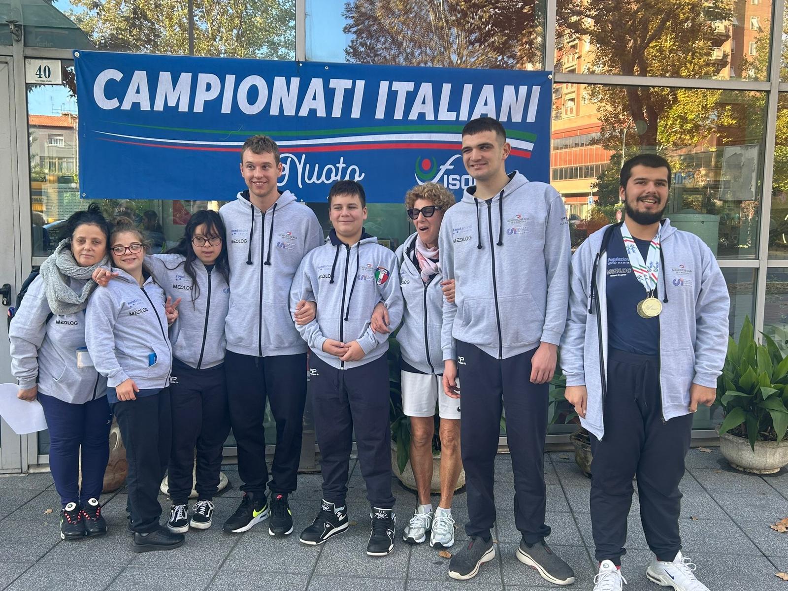 Alcuni ragazzi e ragazze davanti a un cartello con scritto "Campionati italiani"