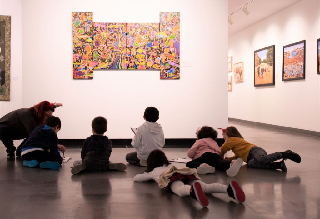 Alcuni bambini a terra davanti a un quadro, mentre ascoltano una storia