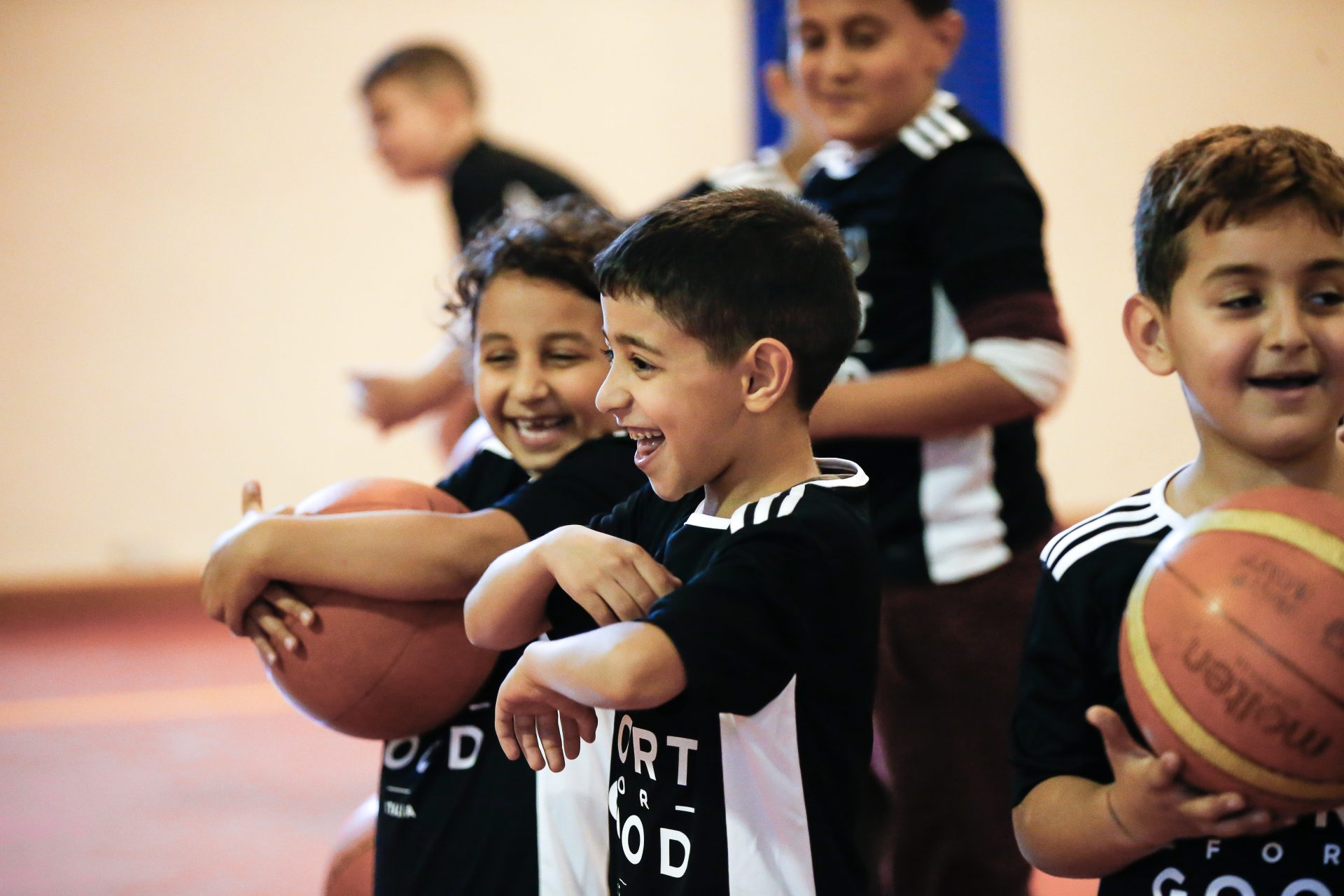 Bambini sorridenti vestiti in abito sportivo, uno ha una palla da basket in mano