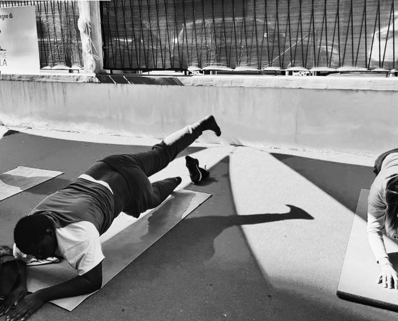 Foto in bianco e nero di una persona che fa esercizi di ginnastica sul tappetino