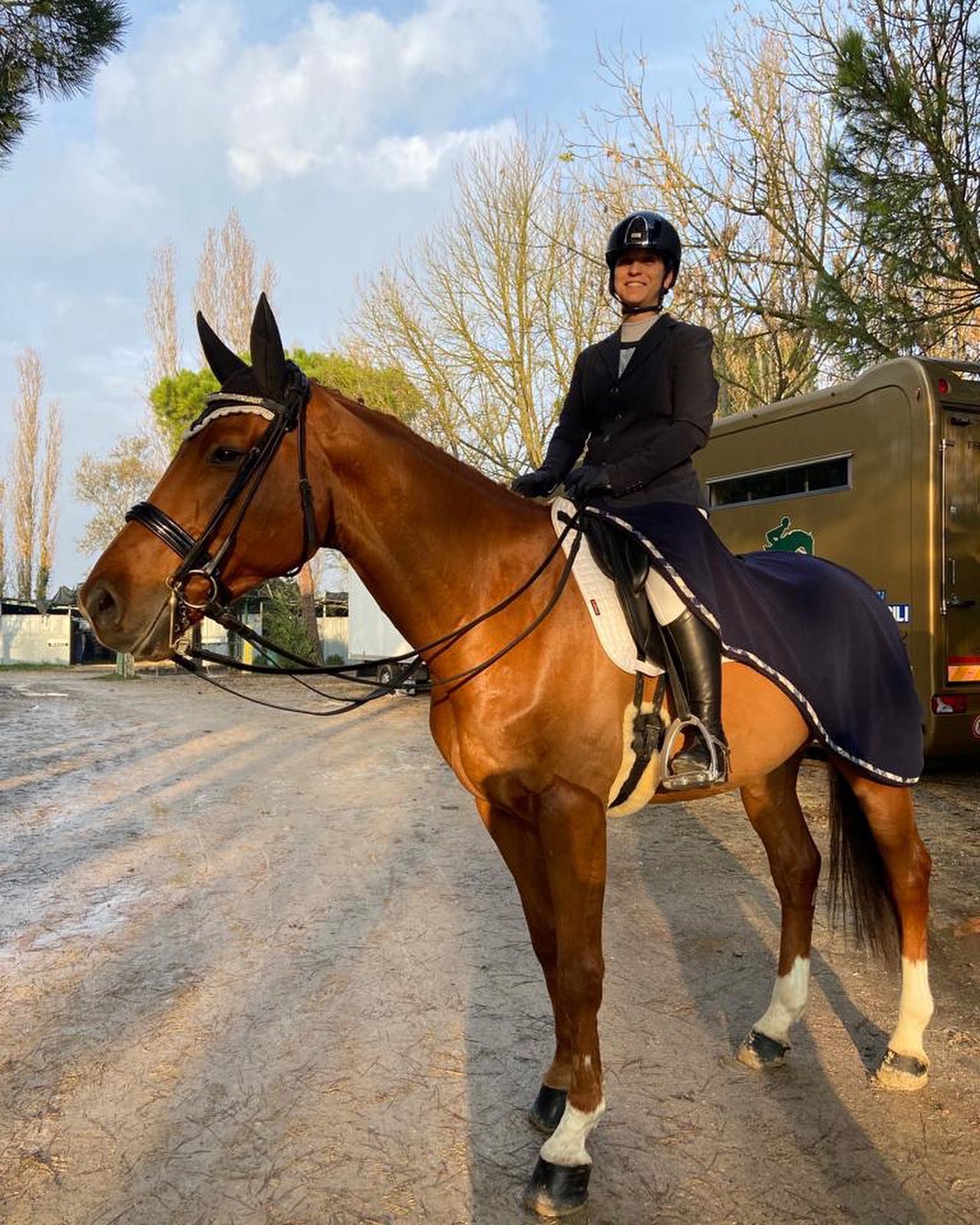 Una persona sorridente a cavallo, con vestiti da fantino