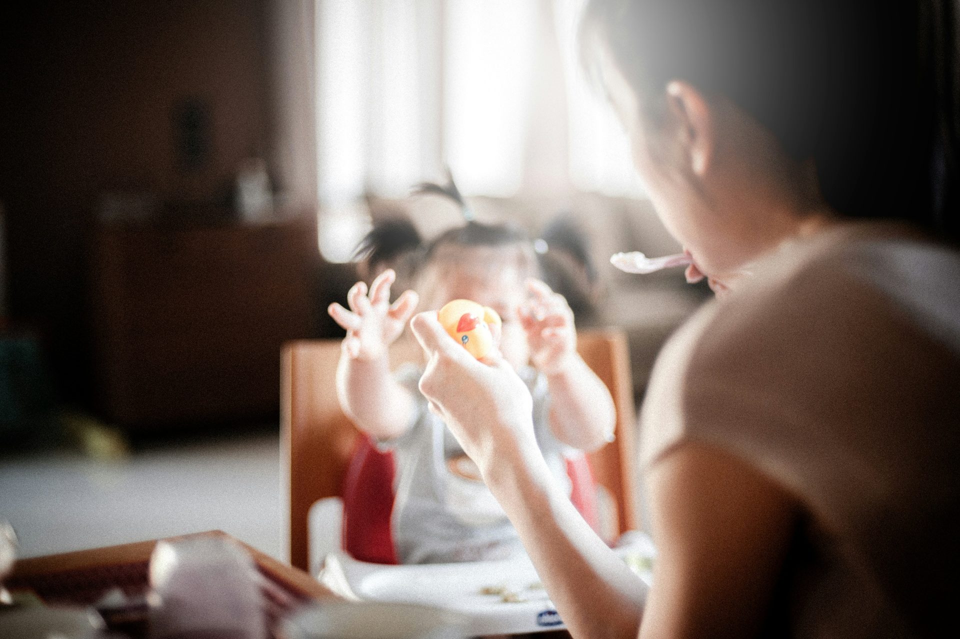 mamma che imbocca una bambina seduta nel seggiolone