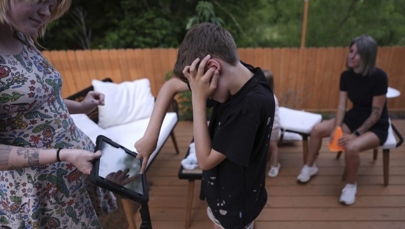 Un ragazzino con diagnosi di autismo, non verbale, comunica con il tablet con la sua caregiver